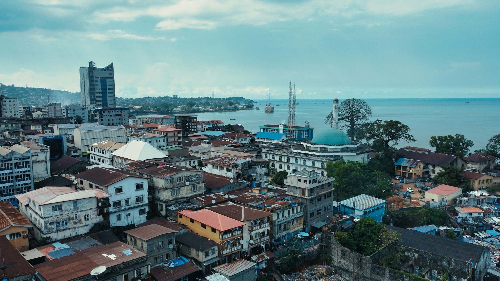 Aerial view of central Freetown, with rooftops, a mosque and the sea behind