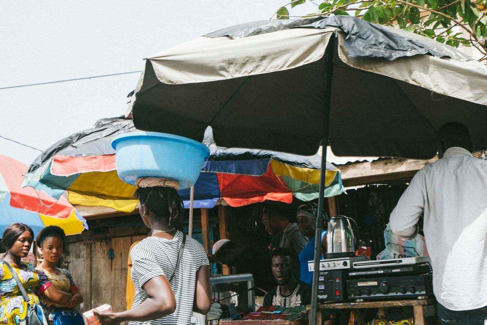 Market stalls under colourful parasols in Freetown, with traders and shoppers